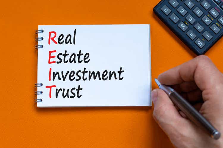 REIT real estate investment trust symbol. Concept words REIT real estate investment trust on the note on beautiful orange background. Business REIT real estate investment trust concept.